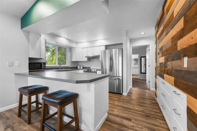 140 E Mountain View Dr, Allyn, WA 98524 - kitchen featuring stainless steel appliances, under cabinet range hood, a peninsula, dark wood finished floors, and white cabinetry