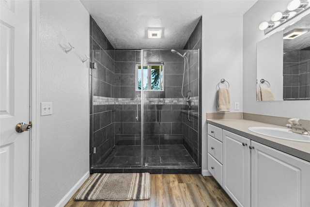 140 E Mountain View Dr, Allyn, WA 98524 - bathroom with vanity, a shower stall, wood finished floors, a textured ceiling, and baseboards