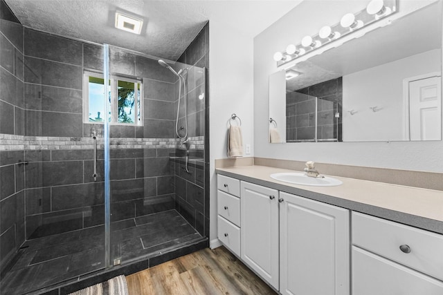 140 E Mountain View Dr, Allyn, WA 98524 - full bath featuring vanity, a shower stall, wood finished floors, and a textured ceiling