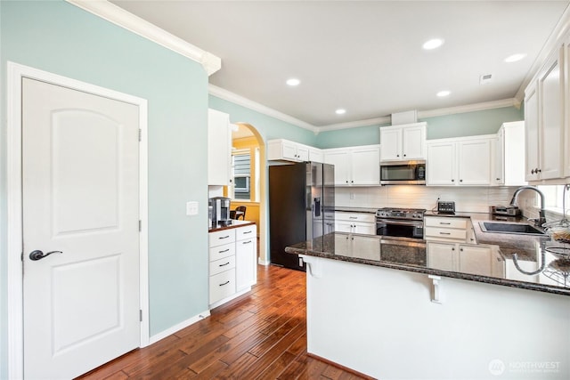2529 10th Ct SE, Olympia, WA 98501 - kitchen with stainless steel appliances, a sink, arched walkways, ornamental molding, and dark wood-type flooring
