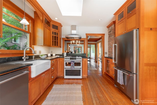 528 N 83rd St, Seattle, WA 98103 - kitchen featuring stainless steel appliances, wall chimney range hood, brown cabinetry, and healthy amount of natural light