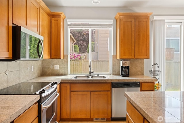 3808 Wildspitz St SE, Lacey, WA 98503 - kitchen featuring appliances with stainless steel finishes, a sink, decorative backsplash, and brown cabinets