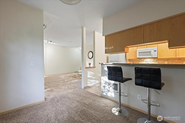 18930 Bothell Everett Hwy Unit V201, Bothell, WA 98012 - kitchen with white microwave, light carpet, a kitchen breakfast bar, and tasteful backsplash
