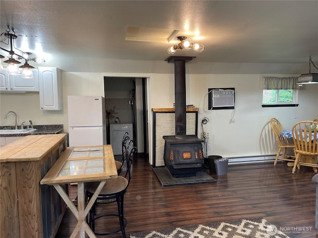 48 Blue Jay Loop, Walla Walla, WA 99362 - dining space with a wood stove, a wall mounted AC, dark wood-style floors, washer / clothes dryer, and a baseboard radiator