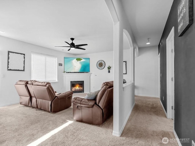 530 N Kentucky Dr, Moses Lake, WA 98837 - living area featuring arched walkways, light carpet, a tile fireplace, a ceiling fan, and baseboards
