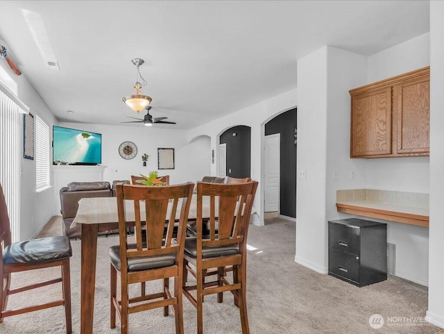 530 N Kentucky Dr, Moses Lake, WA 98837 - dining area featuring light carpet, a ceiling fan, arched walkways, and baseboards