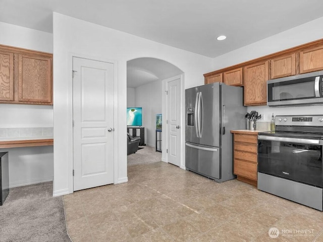 530 N Kentucky Dr, Moses Lake, WA 98837 - kitchen featuring stainless steel appliances, arched walkways, brown cabinetry, recessed lighting, and light countertops