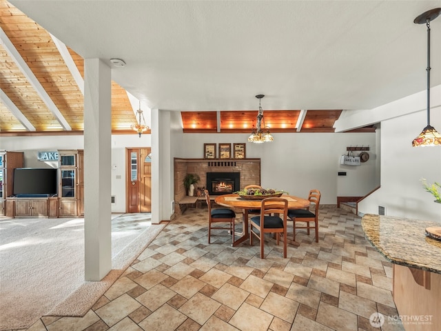 271 E Ballantrae Dr, Shelton, WA 98584 - dining room with a lit fireplace, wooden ceiling with exposed beams, and light stone finish floors