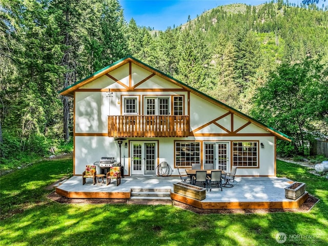 84 Norling Ln, Leavenworth, WA 98826 - rear view of property with french doors, a forest view, a wooden deck, and a lawn
