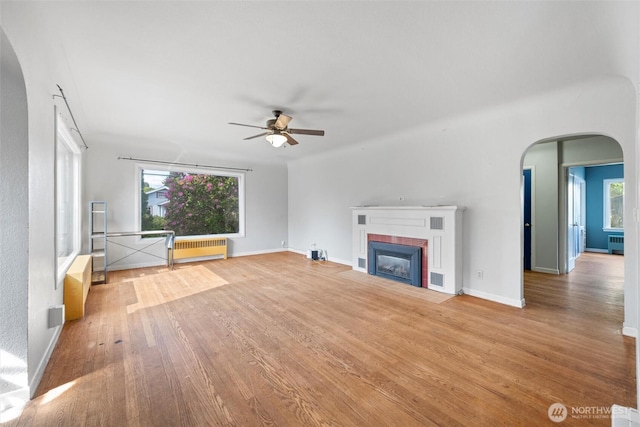 2830 Elm St, Bellingham, WA 98225 - unfurnished living room with ceiling fan, a brick fireplace, radiator heating unit, wood finished floors, and arched walkways