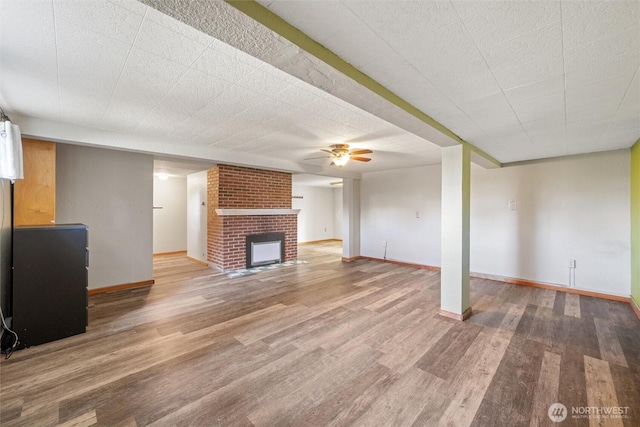 2830 Elm St, Bellingham, WA 98225 - unfurnished living room featuring wood finished floors, baseboards, a ceiling fan, and a fireplace
