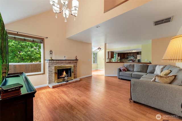 12903 SE 282nd Way, Kent, WA 98030 - living room featuring light wood finished floors, high vaulted ceiling, a chandelier, baseboards, and a brick fireplace