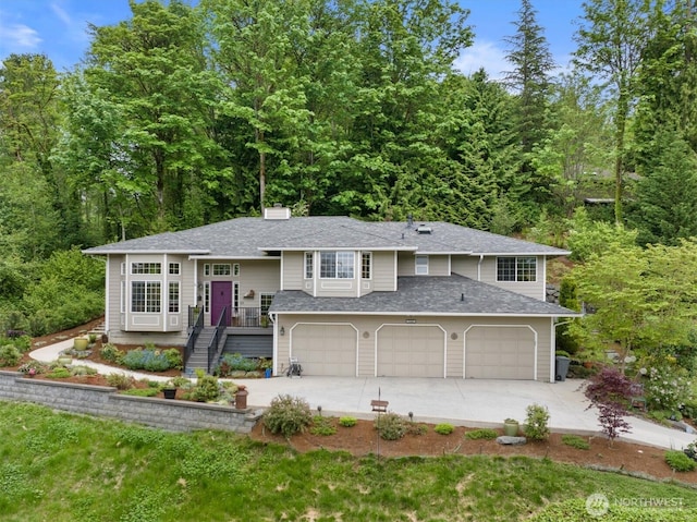 7123 NE 165th St, Kenmore, WA 98028 - bi-level home with concrete driveway, an attached garage, a shingled roof, and a forest view