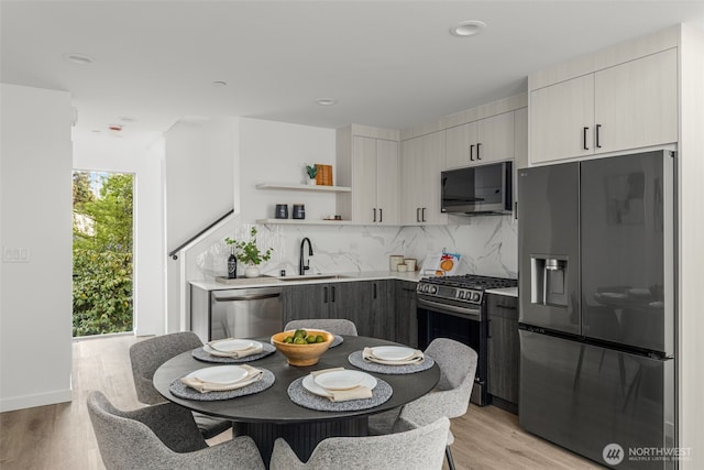 4426 Midvale Ave N, Seattle, WA 98103 - kitchen with appliances with stainless steel finishes, a sink, open shelves, backsplash, and light wood-style floors