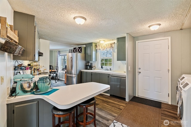4224 N Brooks Rd, Medical Lake, WA 99022 - kitchen with stainless steel appliances, dark wood-style flooring, gray cabinetry, washer and dryer, and a textured ceiling