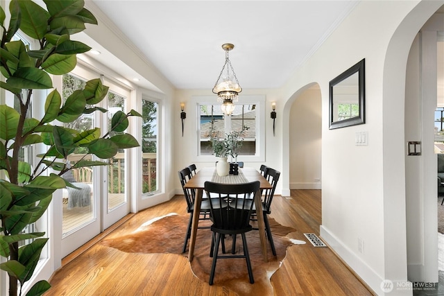 3929 SW Elmgrove St, Seattle, WA 98136 - dining space with arched walkways, baseboards, a chandelier, wood finished floors, and ornamental molding