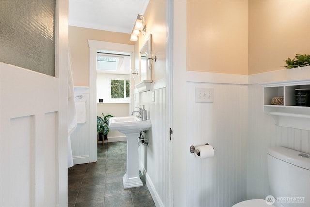 3929 SW Elmgrove St, Seattle, WA 98136 - half bathroom featuring wainscoting, toilet, a decorative wall, ornamental molding, and tile patterned flooring