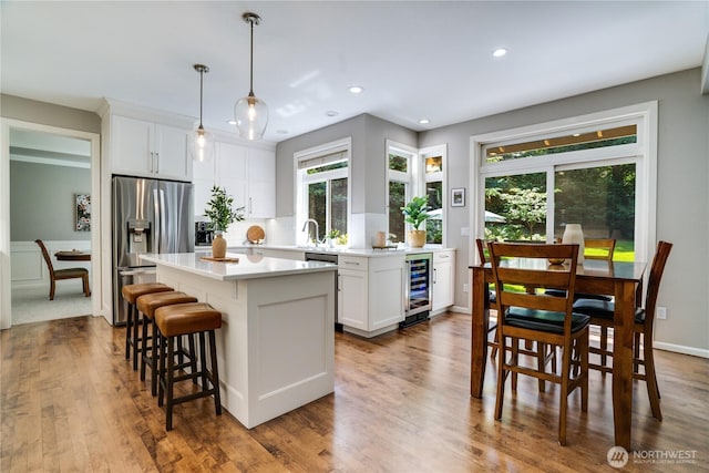 13302 53rd Ave NW, Gig Harbor, WA 98332 - kitchen with wine cooler, stainless steel appliances, a kitchen island, white cabinetry, and a breakfast bar area