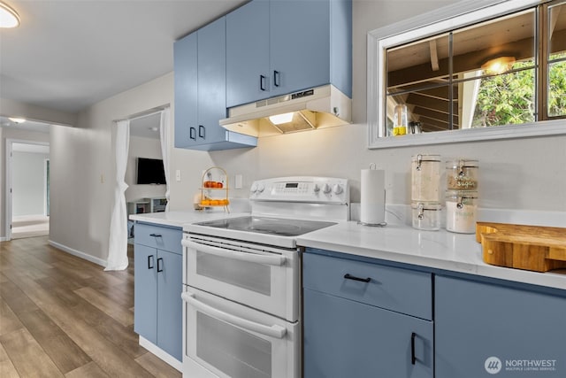5003 219th St SW, Mountlake Terrace, WA 98043 - kitchen featuring range with two ovens, under cabinet range hood, blue cabinets, light countertops, and wood finished floors