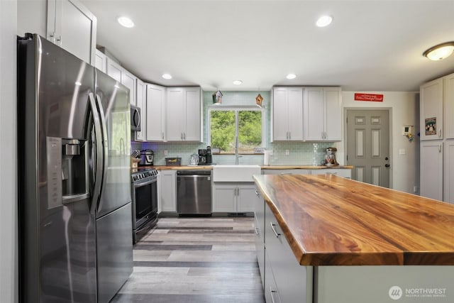 822 Filbert Rd, Cle Elum, WA 98922 - kitchen with appliances with stainless steel finishes, butcher block countertops, a sink, light wood-style floors, and backsplash