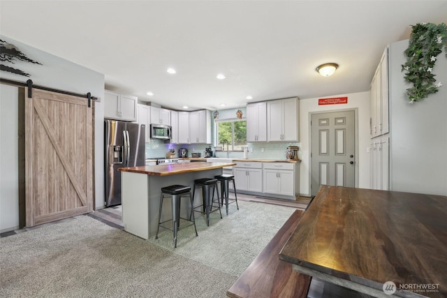 822 Filbert Rd, Cle Elum, WA 98922 - kitchen with appliances with stainless steel finishes, a breakfast bar area, a barn door, tasteful backsplash, and white cabinetry