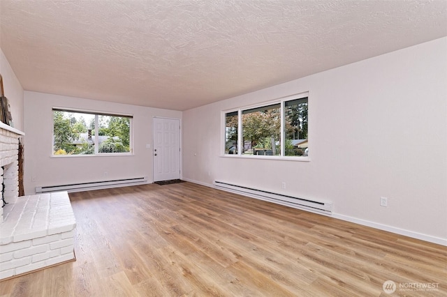 944 Barnhard St, Shelton, WA 98584 - unfurnished living room with baseboard heating, a brick fireplace, wood finished floors, baseboards, and a textured ceiling