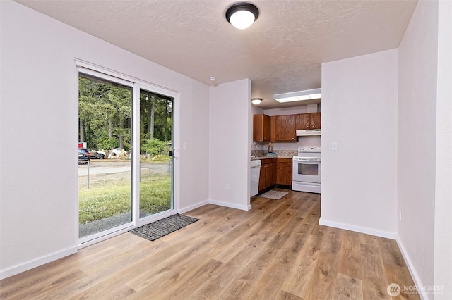 944 Barnhard St, Shelton, WA 98584 - kitchen with white appliances, under cabinet range hood, brown cabinetry, light countertops, and baseboards