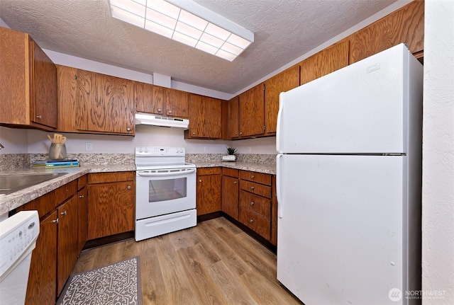 944 Barnhard St, Shelton, WA 98584 - kitchen with white appliances, under cabinet range hood, light wood finished floors, a sink, and brown cabinetry
