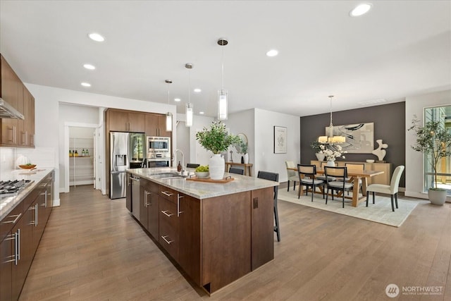 12126NE 106th Pl, Kirkland, WA 98033 - kitchen featuring stainless steel appliances, a sink, recessed lighting, wood finished floors, and a breakfast bar area