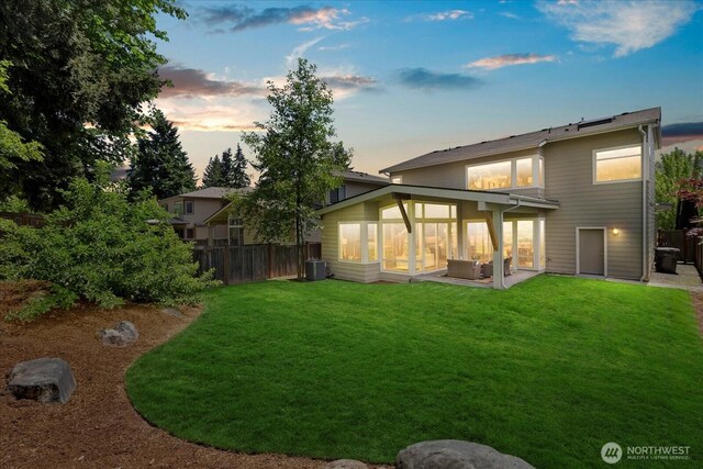 12126NE 106th Pl, Kirkland, WA 98033 - back of house at dusk featuring a sunroom, a patio area, and central air condition unit