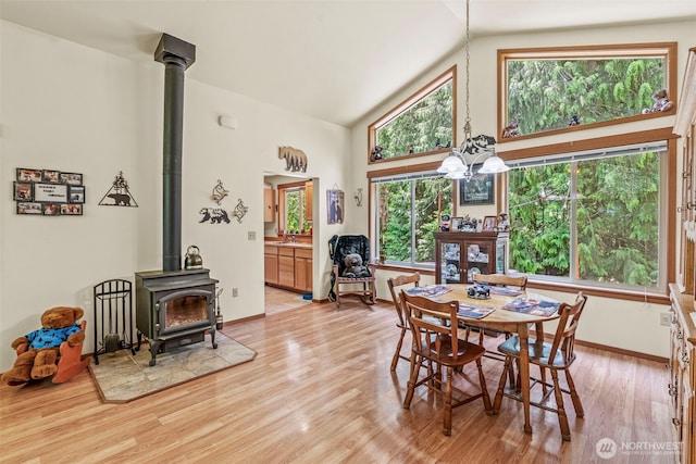 19243 Kiona Rd, Randle, WA 98377 - dining area featuring a wood stove, high vaulted ceiling, light wood-style flooring, and baseboards