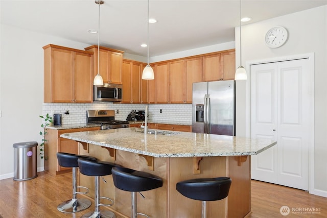 1903 98th Ave SE, Lake Stevens, WA 98258 - kitchen featuring stainless steel appliances, a sink, light wood-style flooring, backsplash, and a kitchen bar