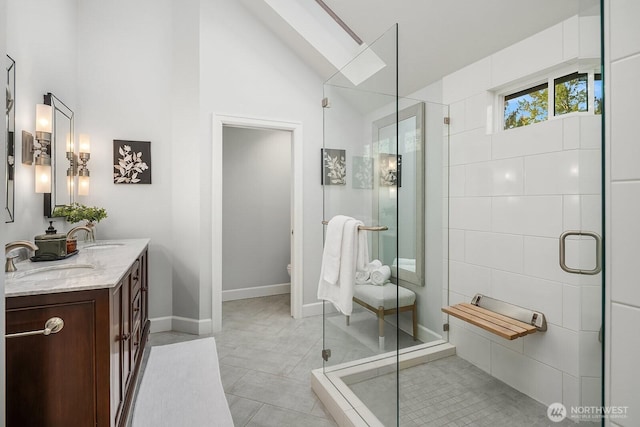 24228 SE 47th St, Sammamish, WA 98029 - bathroom featuring double vanity, lofted ceiling, a stall shower, a skylight, and baseboards