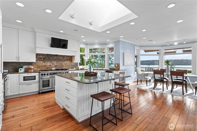 4486 E Harbor Rd, Freeland, WA 98249 - kitchen with double oven range, white cabinets, a kitchen bar, a kitchen island, and tasteful backsplash