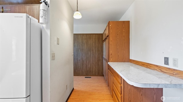 842 W Langdon Rd, Walla Walla, WA 99362 - kitchen with freestanding refrigerator, brown cabinetry, light countertops, light wood-style flooring, and decorative light fixtures