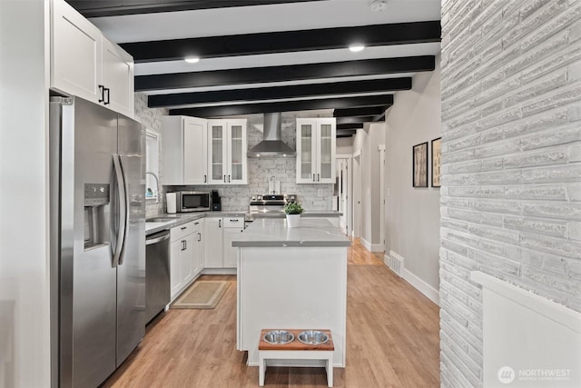 18568 Densmore Ave N, Shoreline, WA 98133 - kitchen featuring stainless steel appliances, wall chimney range hood, white cabinetry, a kitchen island, and beamed ceiling