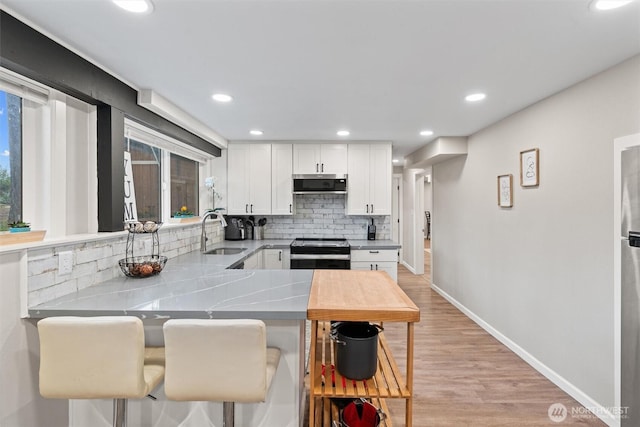 18568 Densmore Ave N, Shoreline, WA 98133 - kitchen featuring range with electric stovetop, white cabinetry, decorative backsplash, stainless steel microwave, and light countertops