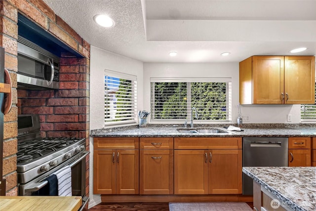 3026 E Alpine Dr, Bellingham, WA 98226 - kitchen featuring appliances with stainless steel finishes, a sink, dark stone counters, a textured ceiling, and brown cabinetry