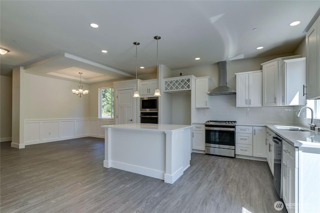 2403 79th Ave SE Unit 110, Tumwater, WA 98501 - kitchen featuring stainless steel appliances, wall chimney range hood, a sink, a chandelier, and wood finished floors