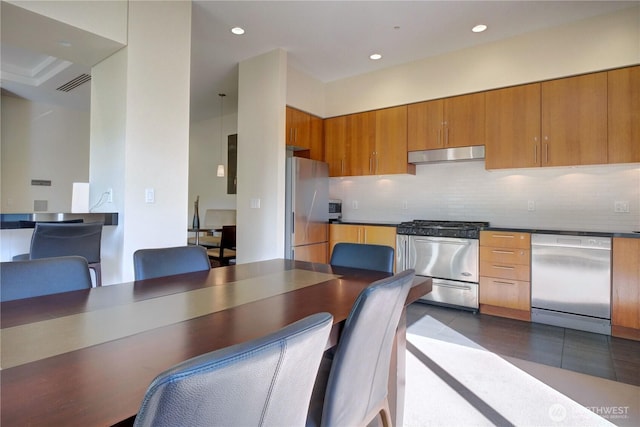 2721 1st Ave Unit Ph06, Seattle, WA 98121 - kitchen featuring appliances with stainless steel finishes, under cabinet range hood, decorative backsplash, brown cabinets, and recessed lighting