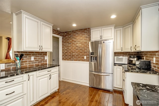 10908 151st St E, Puyallup, WA 98374 - kitchen with stainless steel fridge, white microwave, dark wood-type flooring, a wainscoted wall, and dark stone countertops