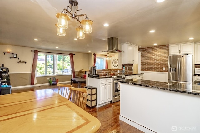 10908 151st St E, Puyallup, WA 98374 - kitchen with stainless steel appliances, wall chimney exhaust hood, white cabinetry, recessed lighting, and a chandelier