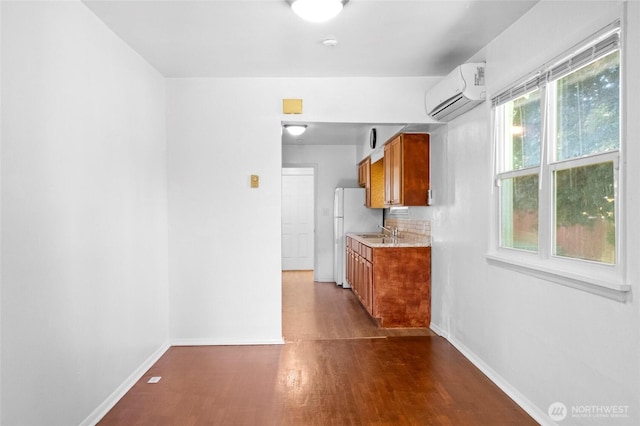 2526 S J St, Tacoma, WA 98405 - kitchen with a wall mounted air conditioner, a sink, brown cabinets, dark wood-style floors, and baseboards
