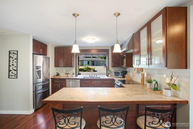 13632 SE Fairwood Blvd, Renton, WA 98058 - kitchen featuring stainless steel appliances, a peninsula, dark wood finished floors, a breakfast bar, and glass insert cabinets