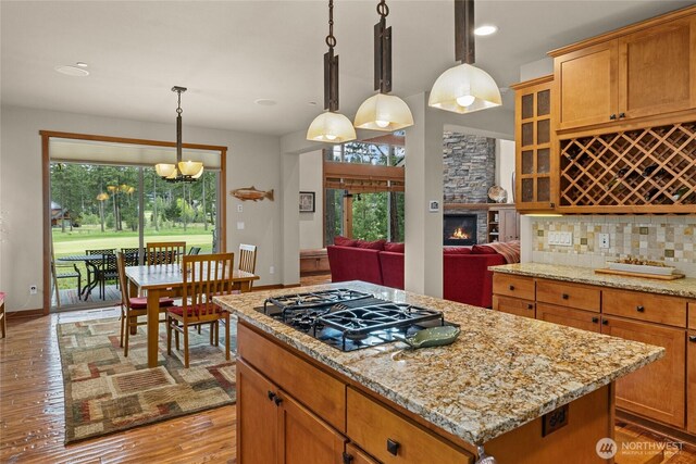 2101 Coal Mine Way, Cle Elum, WA 98922 - kitchen featuring black gas cooktop, a kitchen island, glass insert cabinets, light wood-type flooring, and light stone countertops