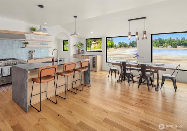 8811 SW Quartermaster Dr, Vashon, WA 98070 - kitchen with high end stainless steel range oven, a sink, an island with sink, decorative backsplash, and a breakfast bar area