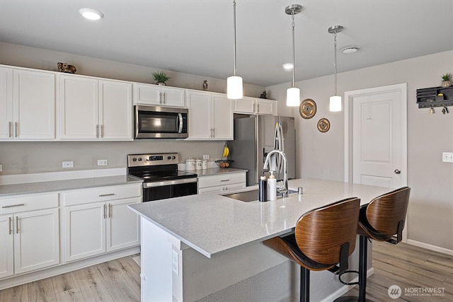 15013 Iverson Loop SE, Yelm, WA 98597 - kitchen with stainless steel appliances, a sink, light wood-type flooring, white cabinets, and a center island with sink