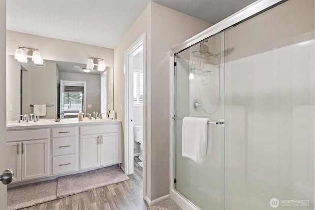 15013 Iverson Loop SE, Yelm, WA 98597 - bathroom with a shower stall, wood finished floors, double vanity, and toilet