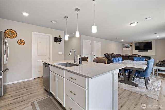 15013 Iverson Loop SE, Yelm, WA 98597 - kitchen with stainless steel appliances, a sink, light wood finished floors, and white cabinets