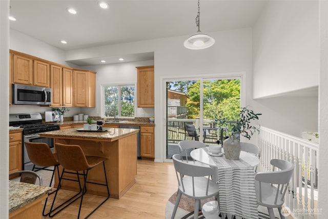 2024 N 145th St, Shoreline, WA 98133 - kitchen with appliances with stainless steel finishes, light wood finished floors, a center island, light stone countertops, and a breakfast bar area